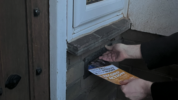 hands pushing a leaflet into a letterbox