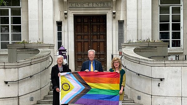 3 councillors holding the pride flag outside city hall