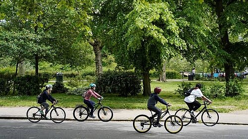 4 children cycling with trees in background
