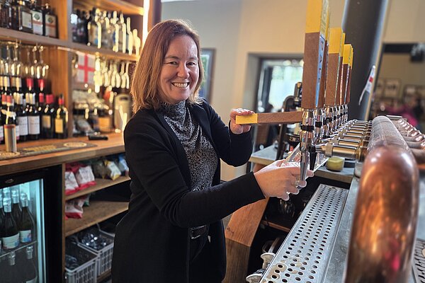 Marie behind a bar smiling